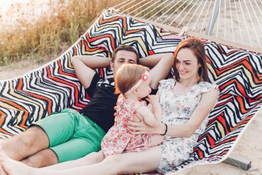 Mutlu aile portresi, Genç hipster baba ve anne bebek kızları, yaz tatili aile gezisi kavramı ile bir hamakta yalan