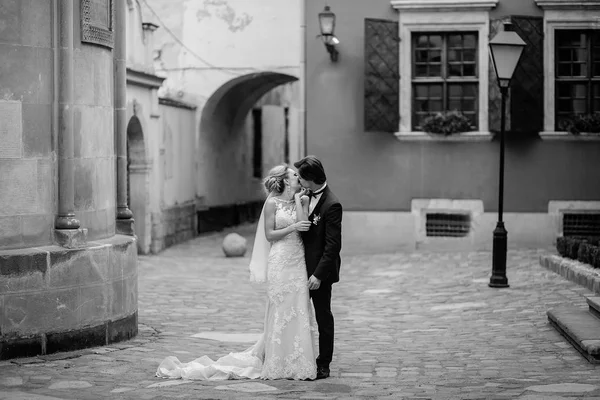 光の広場を歩いて古い建物で豪華な結婚式のカップル スタイリッシュな花嫁と花婿を受け入れ 都市通りでキスします ロマンチックな官能的な瞬間 ブラック ホワイト — ストック写真