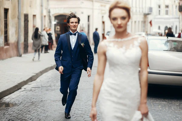 歩いてスタイリッシュな花嫁と花婿の街で彼女の後を実行しています 幸せな豪華な結婚式のカップル ダンスと楽しい ロマンチックな瞬間 — ストック写真