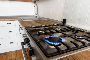şık mutfak iç modern dolaplar ve paslanmaz çelik aletleri ile arka plan üzerinde yanan gaz mutfak ocağı. modern tencere alevlerden. İskandinav tarzında Tasarla