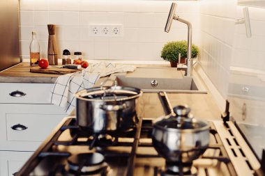 Modern mutfak İskandinav tarzı yemek. modern mobilya ve paslanmaz çelik aletleri ile şık mutfak iç. ahşap tezgah, çelik soba, Masa, bıçak ve baharat, domates