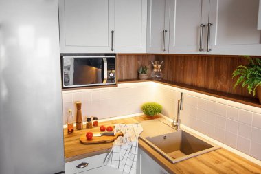 Ahşap tahta bıçak, domates, zeytin yağı modern mutfak tezgah ve Granit Lavabo ve çelik musluk yakınındaki ile. yemek yemek. İskandinav tarzı şık gri mutfak dekorasyon