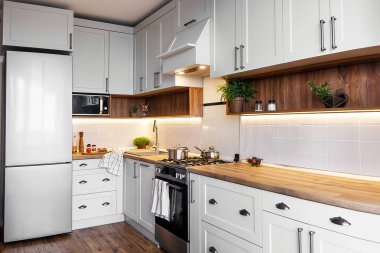Şık mutfak iç modern dolaplar ve paslanmaz çelik araçlarla yeni ev. İskandinav tarzında dizayn. yemek yemek. yeşil bitkiler dekor, ahşap mutfak, lavabo ve soba
