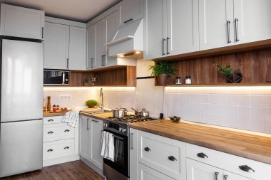 Şık ışık gri mutfak iç modern dolaplar ve paslanmaz çelik araçlarla yeni ev. İskandinav tarzı mutfak tasarımı. yeşil bitkiler dekor, ahşap mutfak, lavabo
