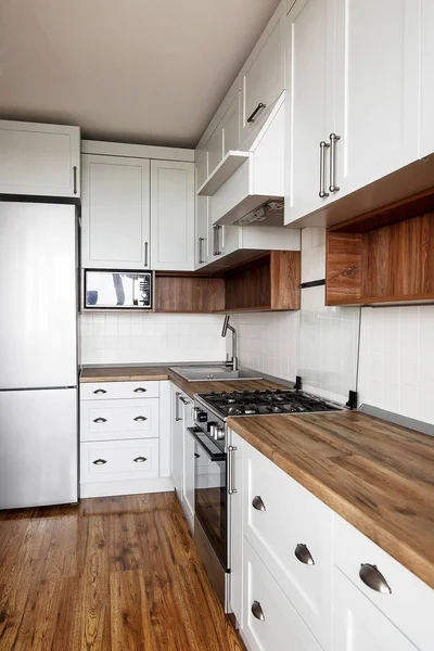 时尚的浅灰色厨房内饰与现代橱柜和不锈钢器具 斯堪的纳维亚风格的厨房设计 硬木地板和木台面 花岗岩水槽和时尚水龙头 — 图库照片