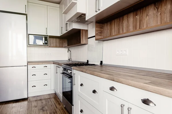 时尚的浅灰色厨房内饰与现代橱柜和不锈钢家电在一个豪华的新房子 斯堪的纳维亚风格的厨房设计 硬木地板和木台面 — 图库照片