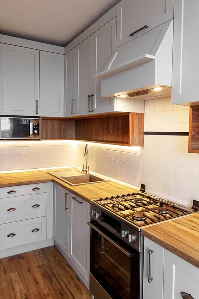 时尚的浅灰色厨房内饰与现代橱柜与轻和不锈钢器具 斯堪的纳维亚风格的厨房设计 现代炊具 木制台面和烟囱 — 图库照片