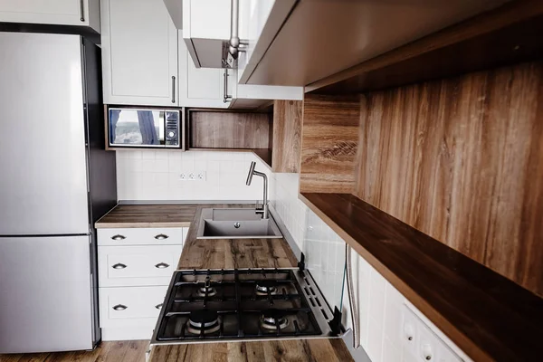 时尚的厨房内饰与现代橱柜和不锈钢家电在一个豪华的新房子 斯堪的纳维亚风格的厨房设计 硬木地板和木台面 空架子 — 图库照片