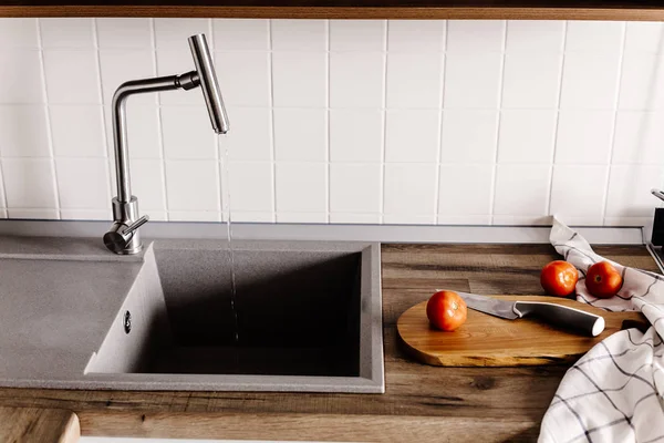 Ahşap tahta bıçak, domates, havlu, baharatlar modern mutfak tezgah üstü Granit Lavabo ve çelik musluk su ile yakın tarih. yemek yemek. Şık gri mutfak iç