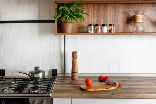 karabiber değirmeni, bıçak, modern mutfak tezgah ve raflar cam kavanoz içinde baharatlar ile domates ile ahşap tahta. yemek yemek. İskandinav tarzı şık gri mutfak dekorasyon