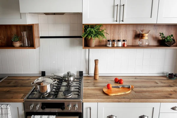 Şık mutfak iç modern dolaplar ve paslanmaz çelik araçlarla yeni ev. İskandinav tarzında dizayn. yemek yemek. yeşil bitkiler dekor, ahşap mutfak, lavabo ve soba