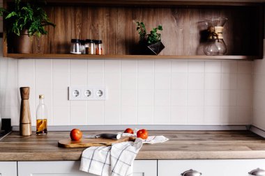 Ahşap tahta bıçak, zeytin yağı, domates, modern mutfak tezgah ve baharatlar ve bitkiler ile raf havlu ile. yemek yemek. İskandinav tarzı şık mutfak dekorasyon