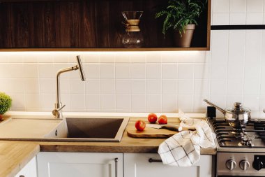 Ahşap tahta bıçak, modern mutfak tezgah Granit Lavabo ve çelik musluk yanında domates ile. yemek yemek. Şık mutfak iç tasarımında İskandinav tarzı, çelik aletleri