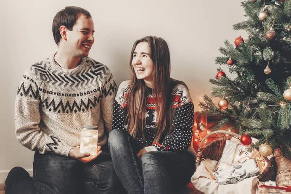 şık kazak Noel ağacı ve gülümseyen Festival odasında fener ışık tutan mutlu çift. atmosferik şenlikli anlar. mutlu Noeller ve mutlu yeni yıl kavramı