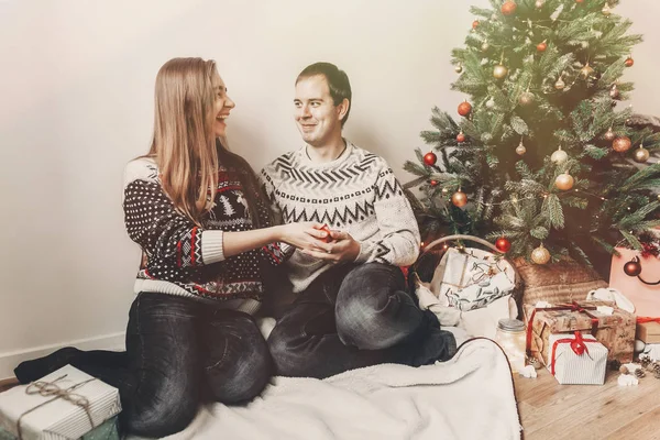 mutlu Noeller ve mutlu yeni yıl kavramı. şık hipster çift hediyeler Noel ağacı ışıkları, metin için yer altında Festival odasında ile değiş tokuş. İyi Bayramlar. Aile atmosferik anlar