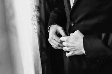şık siyah takım elbise, beyaz gömlek ve kravat giymeyi damat. adam ellerini. sabah hazırlıkları düğün günü önce. damat kıyafeti. hazırlanıyorum. siyah ve beyaz