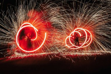 Yangın dansçılar salıncak, iplik kırmızı ateş ve gece ile parlak kıvılcımlar hokkabazlık adam. ateş gösterisi performansını ve eğlence. Yangın gösteri festivalinde geceleri şaşırtıcı veya parti düğün