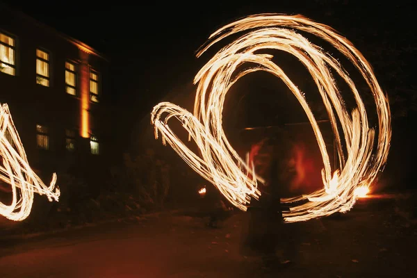 Fire dancers swing, spinning fire and man juggling with bright sparks in the night. fire show performance and entertainment. amazing fire show at night at festival or wedding party.