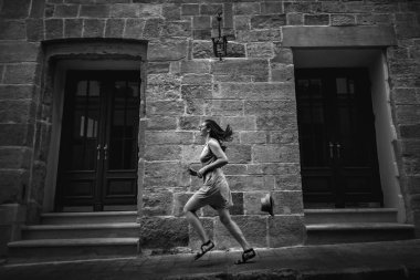 çalışan ve having fun güneşli sabah, siyah ve beyaz fotoğraf eski Avrupa sokaklarda şık kadın hipster