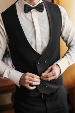 Damat odaya sabah hazırlanıyor. adam üzerine koyarak ceket ve papyon, otel ışık penceresinde ayakta eller. Düğün günü için hazırlık