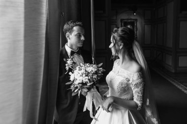 şık damat lüks otel odasında şaşırtıcı kokulu şık elbiseli güzel gelini bakarak. güzel bir kadın damat arıyorum. Evlilik çift kucaklayan. romantik an