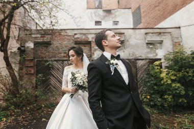 Muhteşem düğün çifti eski binasında poz. şık gelin buketi ve Avrupa City sonbahar zamanında sokak kucaklayan damat ile. Yeni evliler romantik duygusal an