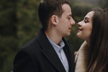 karlı kış parkta sarılma muhteşem evlilik çift. ceket ve kış ormandaki ağaçlar altında kucaklayan damat şık gelin. Yeni evliler romantik duygusal an