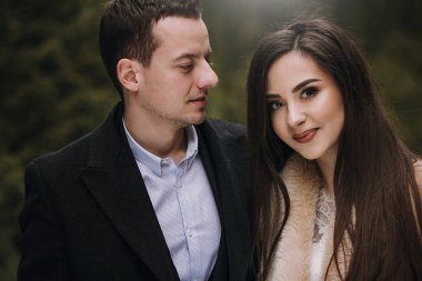 yavaşça karlı kış parkta sarılma muhteşem evlilik çift. ceket ve kış ormandaki ağaçlar altında kucaklayan damat şık gelin. Yeni evliler romantik duygusal an