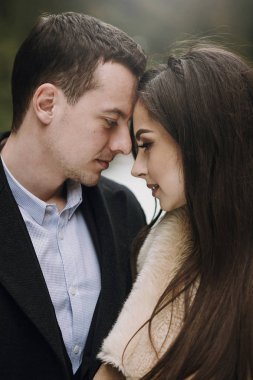 yavaşça karlı kış parkta sarılma muhteşem evlilik çift. ceket ve kış ormandaki ağaçlar altında kucaklayan damat şık gelin. Yeni evliler romantik duygusal an