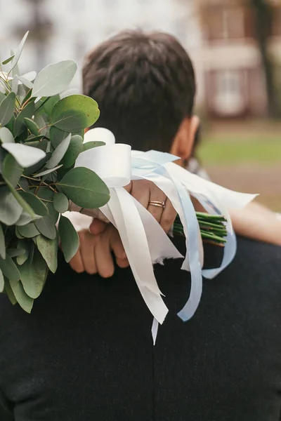 ヨーロッパの街で花束ハグ スタイリッシュな新郎とゴージャスな花嫁 幸せの結婚式を採用します 花と首に手のクローズ アップ ロマンチックな官能的な瞬間 — ストック写真