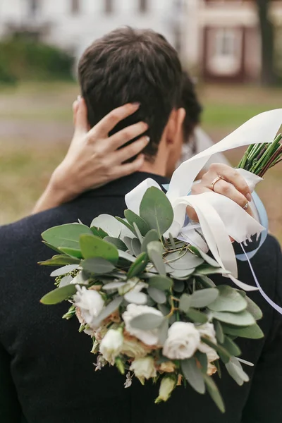 ヨーロッパの街で花束ハグ スタイリッシュな新郎とゴージャスな花嫁 幸せの結婚式を採用します 花と首に手のクローズ アップ ロマンチックな官能的な瞬間 — ストック写真