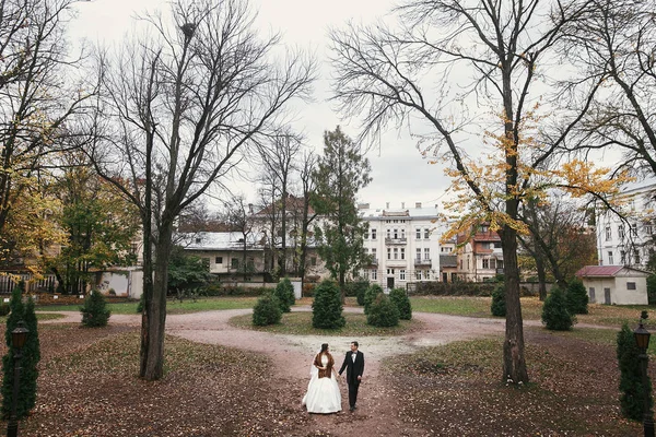 ゴージャスな花嫁の花束と秋の時間のヨーロッパの公園で古いお城で歩いてスタイリッシュな新郎 幸せの結婚式を採用します 新婚夫婦のロマンチックな官能的な瞬間 — ストック写真