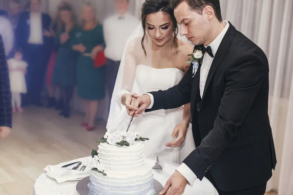 豪華なスタイリッシュな新郎新婦のレストランでの結婚披露宴で花の装飾とスタイリッシュなウェディング ケーキをカットします 幸せな新婚カップルの感動的な瞬間 — ストック写真