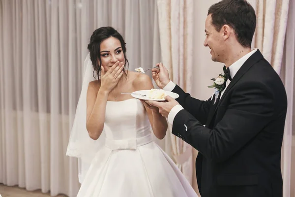 Wunderschöne Braut Und Stilvoller Bräutigam Beim Verkosten Ihrer Stilvollen Hochzeitstorte — Stockfoto