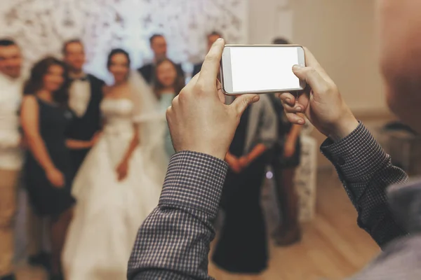 Рука Тримає Телефон Порожнім Екраном Фотографує Щасливу Весільну Пару Гостей — стокове фото