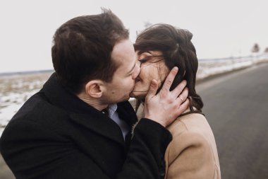 rüzgarlı saç ve damat yolda kucaklayan şehvetli gelinle. mutlu çift, sarılma ve öpüşme rüzgarda romantik ihale ve cinsel an duygusal çift düğün.