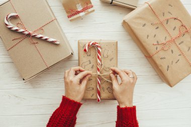 kadın kırmızı kazaklı kaydırma şık e Noel hediye ve şeker kamışı kırmızı elbise. Modern craft Beyaz ahşap arka plan üzerinde sunuyor. neşeli Noel kavramı. düz lay