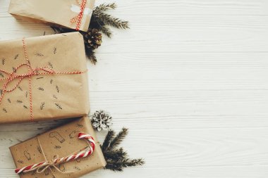 şık basit Noel hediyesi ile kırmızı kurdele, şeker kamışı, Çamın dalları, metin için yer. Modern craft hediyeler düz beyaz ahşap zemin üzerinde yatıyordu. mevsimlik tebrik kartı.