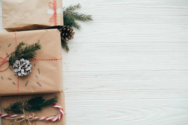 şık basit Noel hediyesi ile kırmızı kurdele, şeker kamışı, Çamın dalları, metin için yer. Modern craft hediyeler düz beyaz ahşap zemin üzerinde yatıyordu. mevsimlik tebrik kartı.