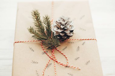 neşeli Noel kavramı. kırmızı kurdele, Çamın dalları, koni ile şık hediye. modern el sanatları Hediyelik Beyaz ahşap zemin üzerinde. mevsimlik tebrik kartı