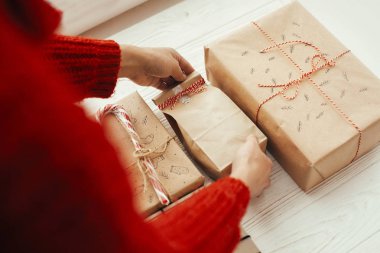 Şık Noel kaydırma eller kırmızı kurdele ile mevcut. Beyaz ahşap zemin üzerinde modern craft hediyeler. neşeli Noel kavramı.