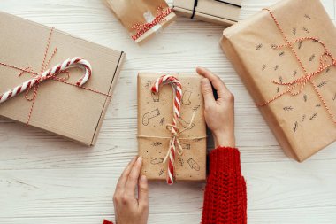 neşeli Noel kavramı. düz yatıyordu. Şık Noel holding eller şeker kamışı ve kurdele ile mevcut. Beyaz ahşap zemin üzerinde modern craft hediyeler. mevsimlik selamlar