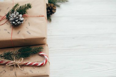 neşeli Noel kavramı. şık kırmızı kurdele, hediyelerle şeker kamışı, Çamın dalları, koniler. Beyaz ahşap arka plan, metin için yer üzerinde modern craft hediyeler. mevsimlik selamlar