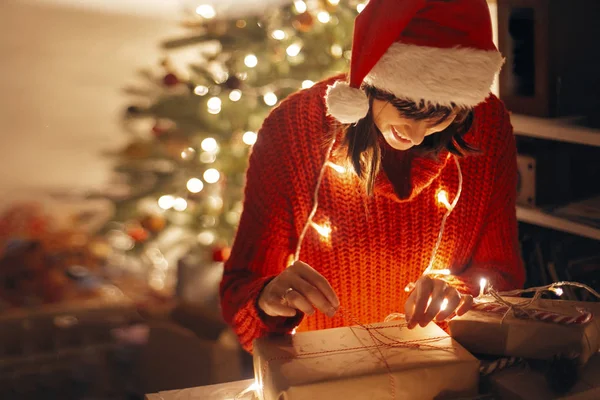 Счастливая Девушка Шляпе Санты Красном Свитере Заворачивая Рождественские Подарки Огни — стоковое фото