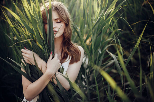 Sensual brunette woman embracing green grass standing in cane. summer vacation. save environment concept