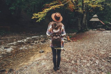 Orman dağlarında yürüyüş sırt çantası ile şapkalı şık hippi kız. Gezgin kadın ormanda keşfetmek. seyahat ve Yolculuk tutkusu kavramı. Atmosferik an, metin için yer