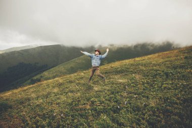 dağlar bulutlar ile üstüne atlama şapkalı şık seyahat adam. metin için yer. hipster seyahat, komik duygular adam. muhteşem atmosferik an. seyahat ve Yolculuk tutkusu kavramı