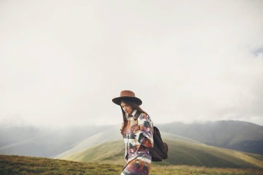 Gezgin hipster bulutlar puslu güneşli dağlarda inceleme sırt çantası ile şapkalı kız. metin için yer. şık kadın seyahat. muhteşem atmosferik an. seyahat ve Yolculuk tutkusu kavramı.