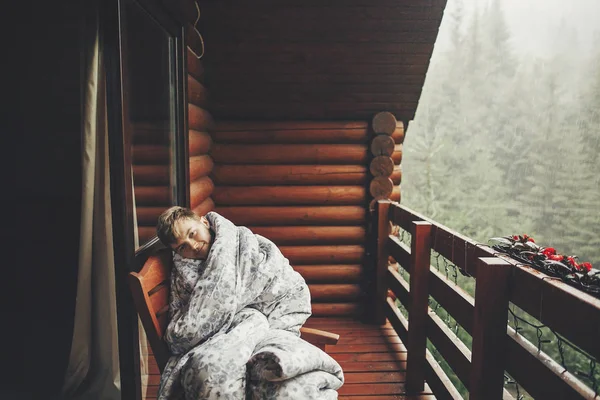 时髦的胡子男子放松在木廊之间的森林在雨季山 时髦的家伙躺在毯子 坐在平房露台 而在树林里下雨 平静的和平时刻 — 图库照片