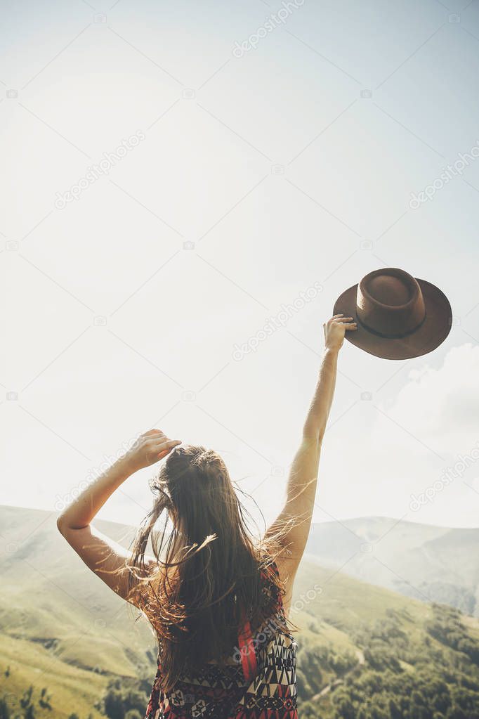 traveler hipster girl holding hat, walking in sunny mountains. summer vacation. space for text. amazing atmospheric moment. happy woman traveling. travel and wanderlust concept